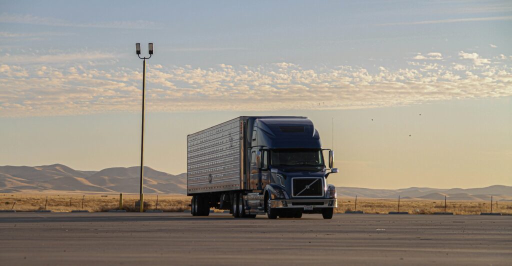 A delivery truck parked at sunset in an open lot 